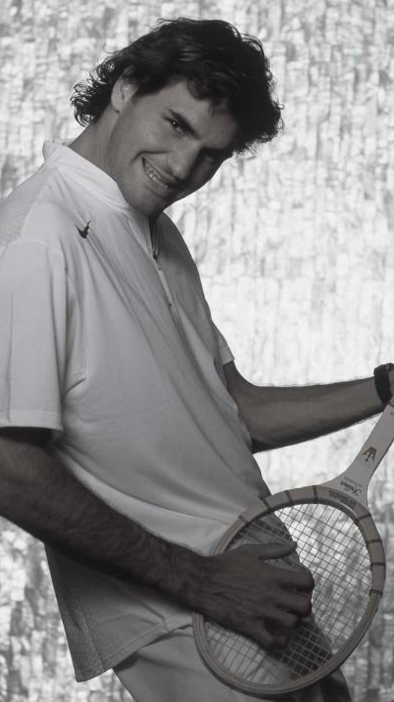 roger federer with long hair playing a tennis racket 